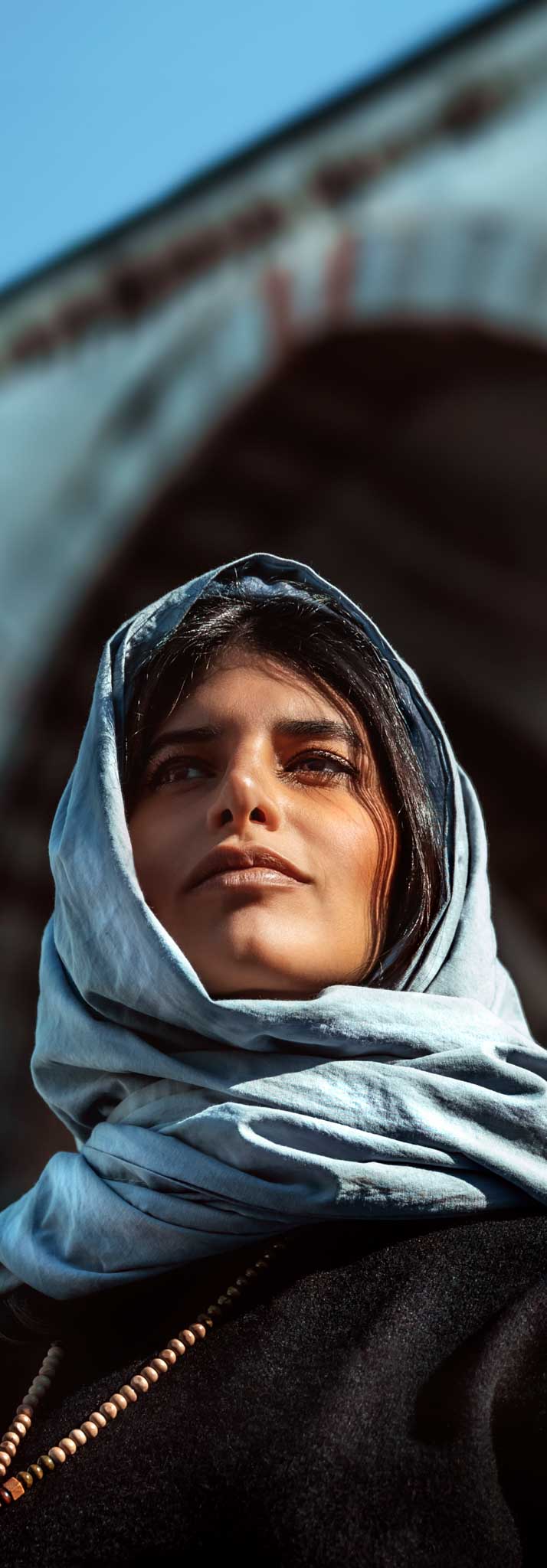 Closeup photo of an attractive arabic woman standing near mosque with covered head by stylish scarf, arabian fashion.