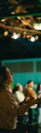 Woman with lifted hands worshiping at Engedi Español, a Spanish-speaking church in Holland Michigan.